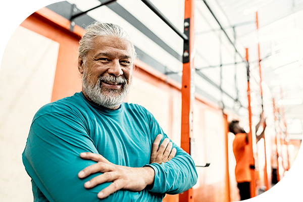 Hombre con barba y brazos cruzados en un gimnasio.